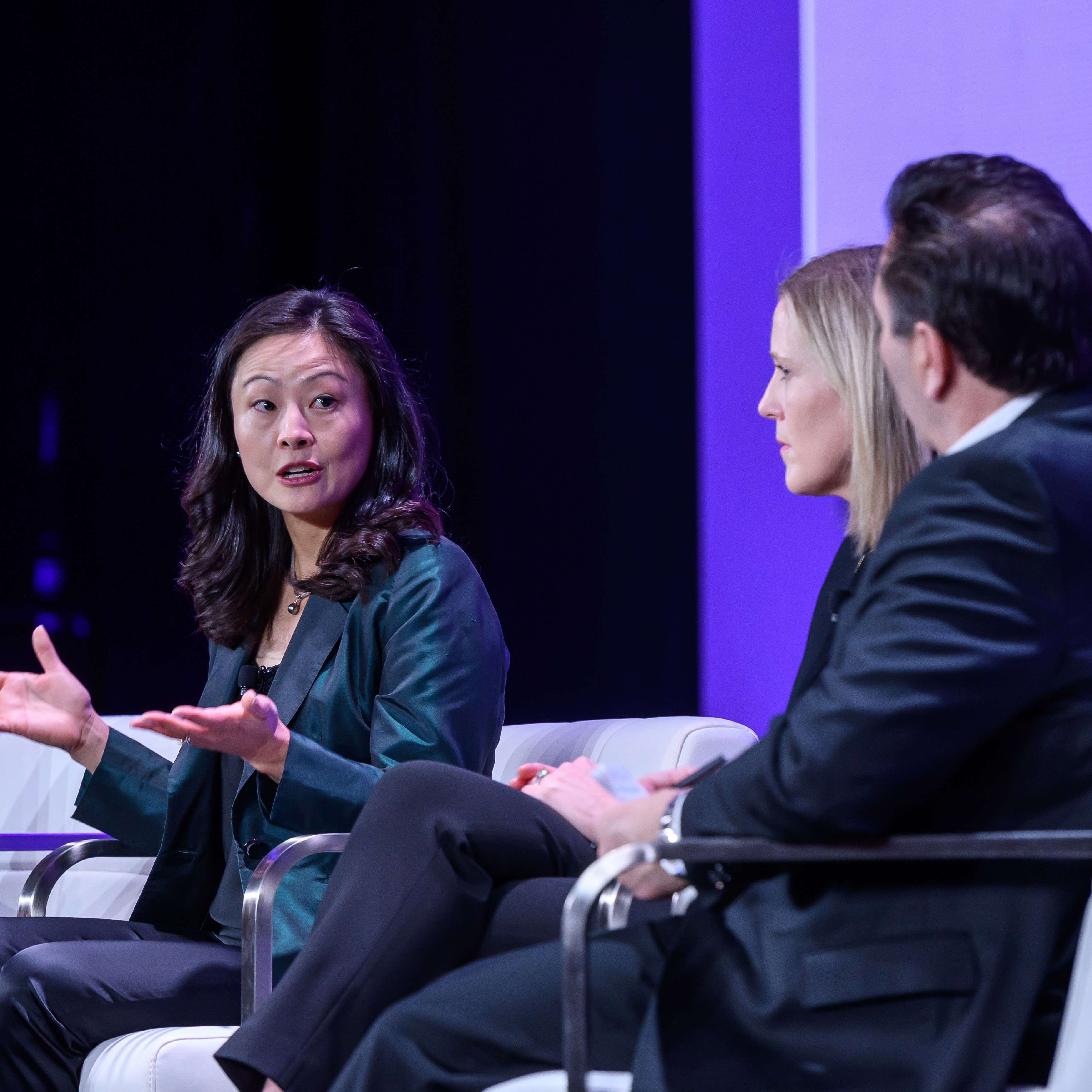 A woman speaks on a panel discussion onstage