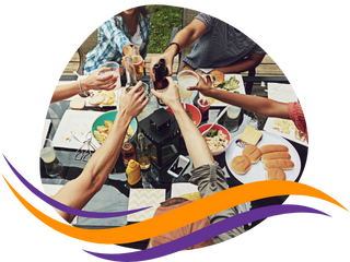 A photo of a circle of people toasting with drinks over a picnic table. 