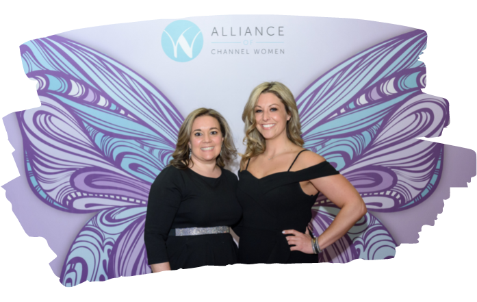 A photo of two women standing in front of a backdrop with the Alliance of Channel Women Logo on it. 